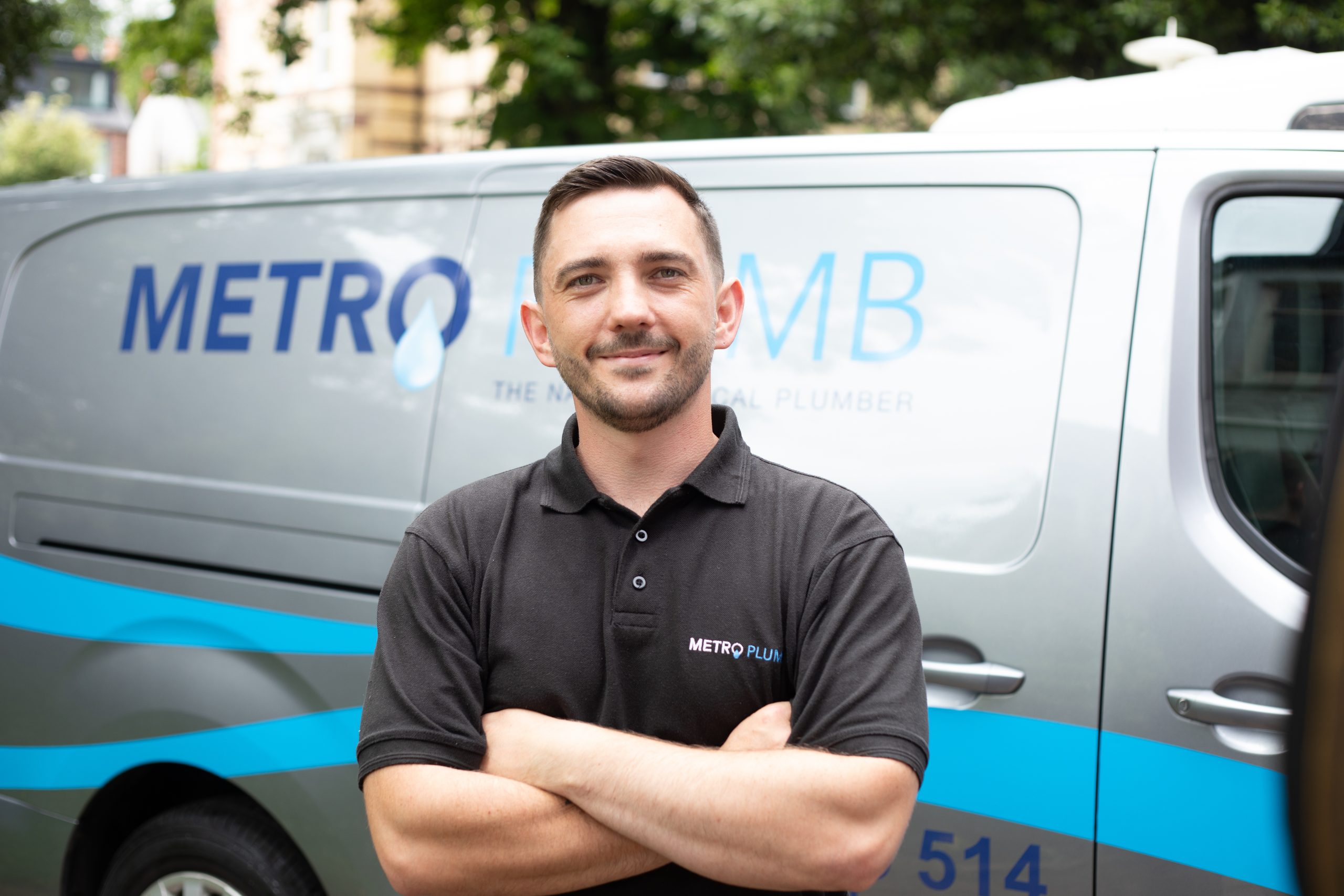 Smiling Metro Plumb Engineer, in front of a Metro Plumb van.