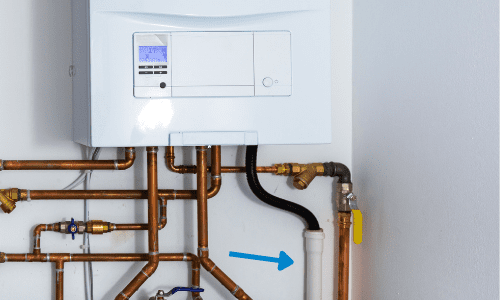 Image of a boiler with copper pipes underneath and a blue arrow pointing to the condensation pipe.