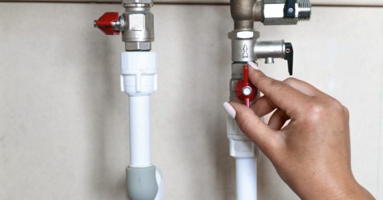 Image of a hand turning an internal red stop valve to represent the action of turning off the water supply.