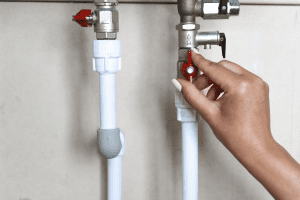 Image of a hand turning a red stop tap valve, symbolising the action of turning off the water supply.