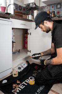 A picture of a Metro Plumb plumber installing a Halcyan unit under a sink